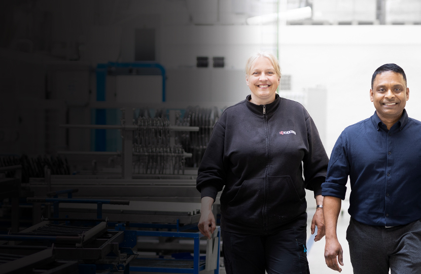 Un grupo de empleados diferentes camina por el pasillo del área de producción, mirando directamente a la cámara.