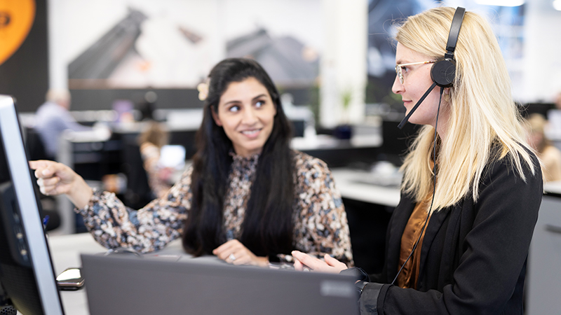 2 colleagues in the office helping out a customer on the phone