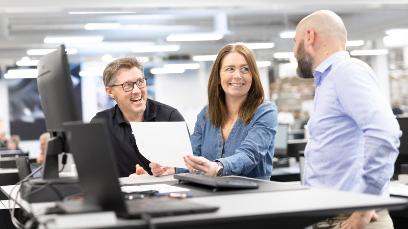 Three colleagues are having fun while cooperating at one's office space