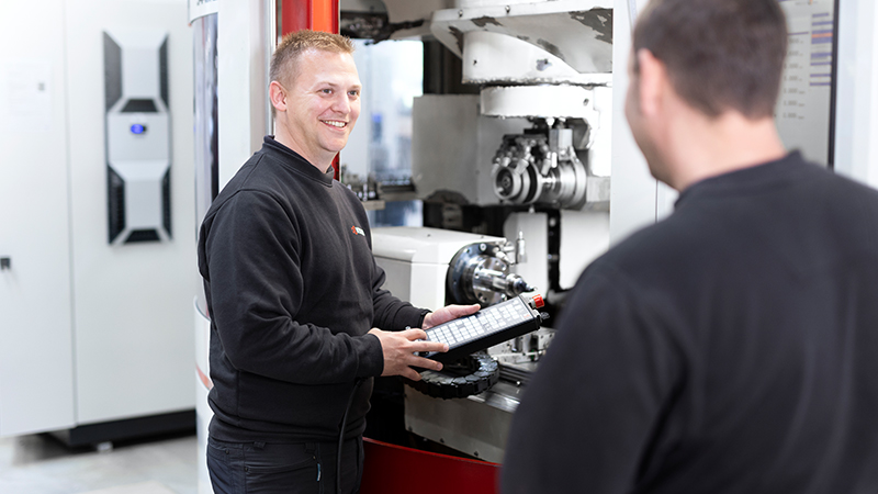 2 colleagues having a conversation next to a Saacke CNC machine