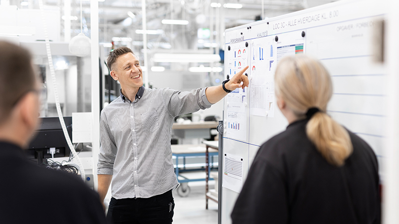 Ein Mann steht bei einer Besprechung vor einem Whiteboard